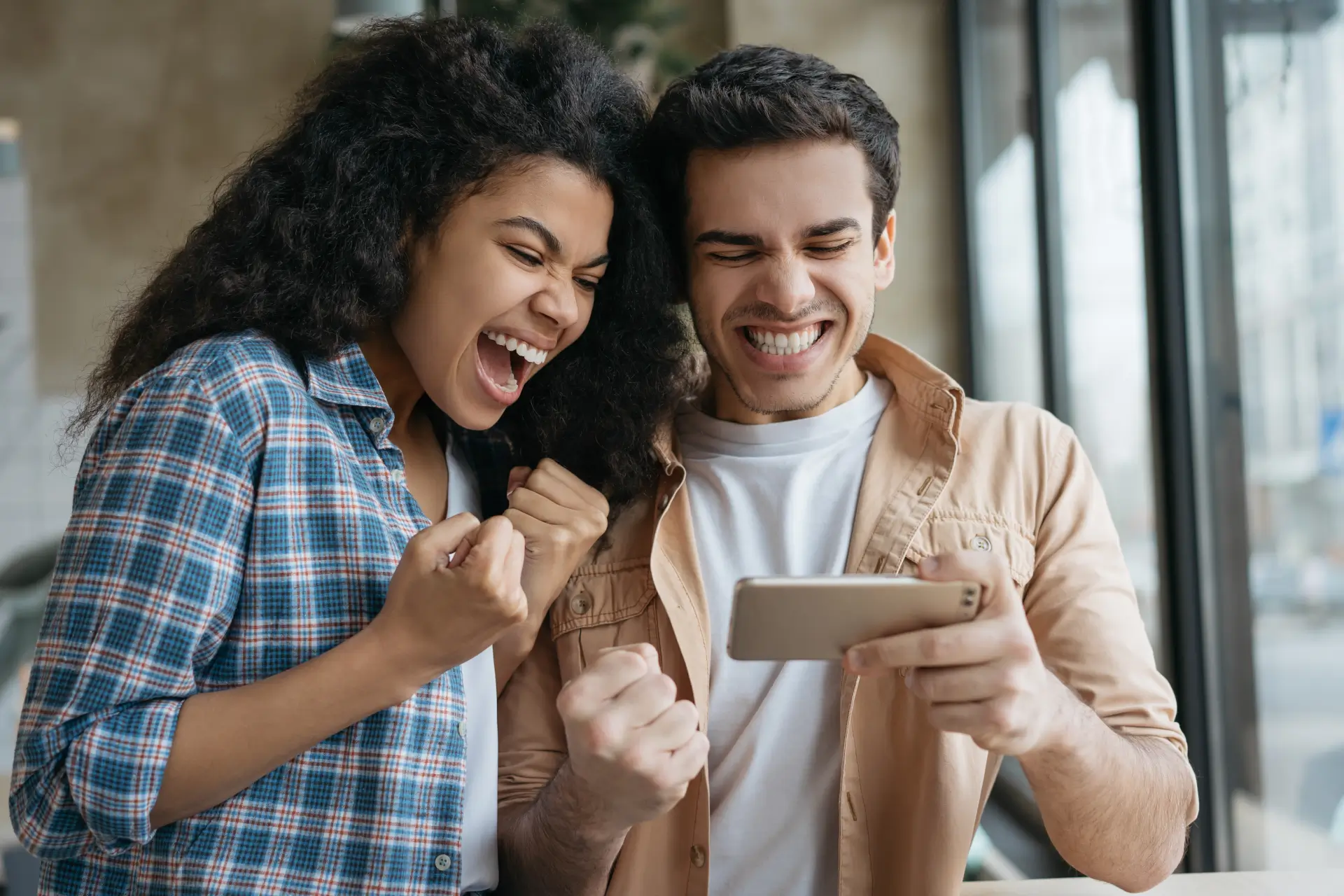 A young woman and man are excited as they look at a smart phone