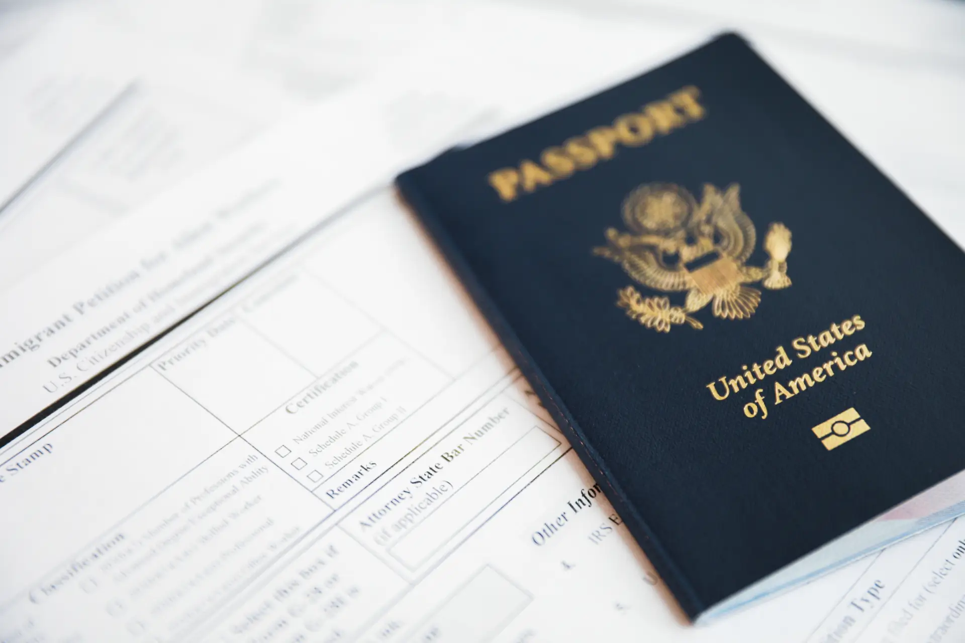 A United States of America passport sits on top of Immigrant Petition forms
