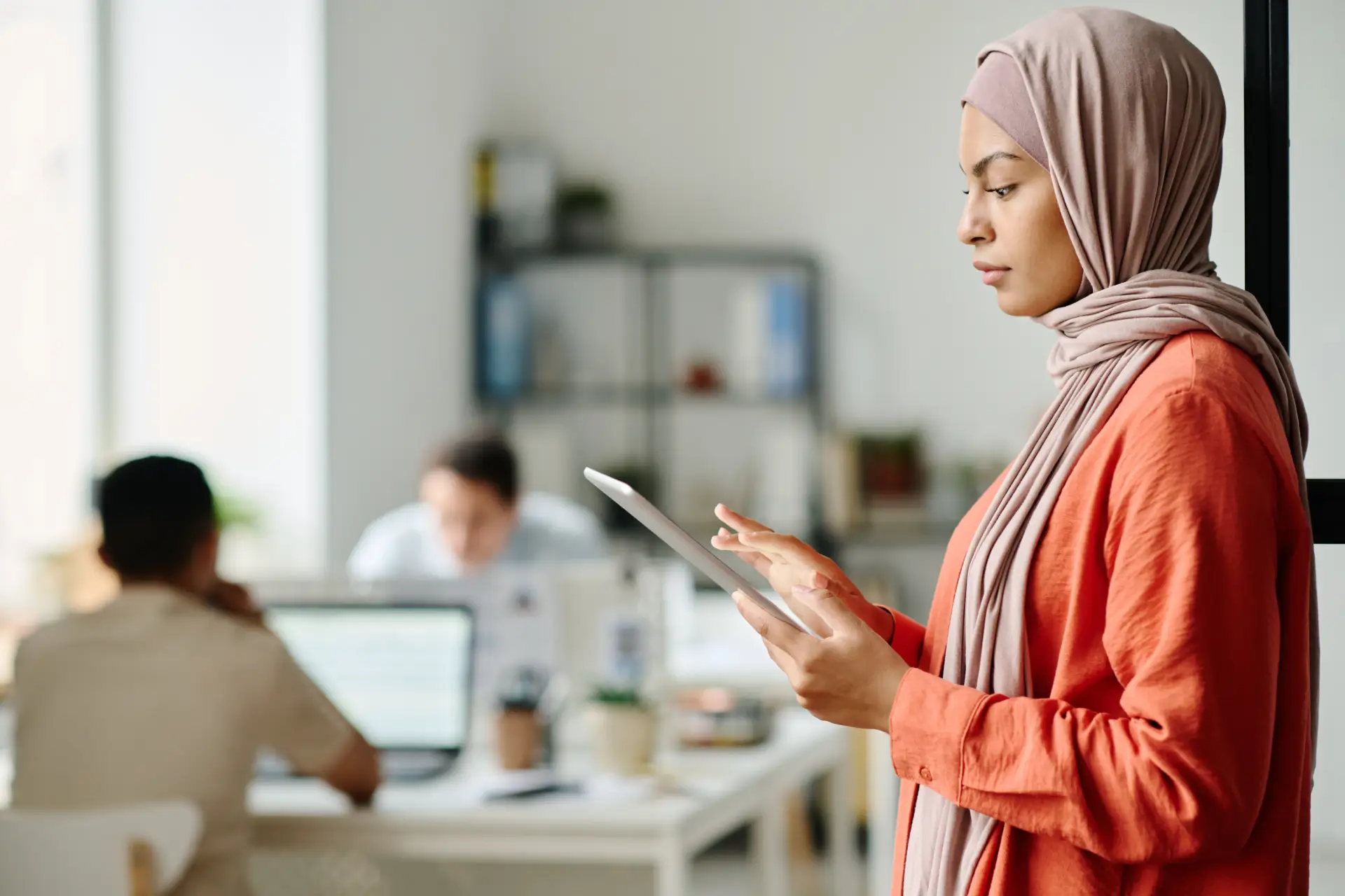 A woman looks through something on a tablet in her hand